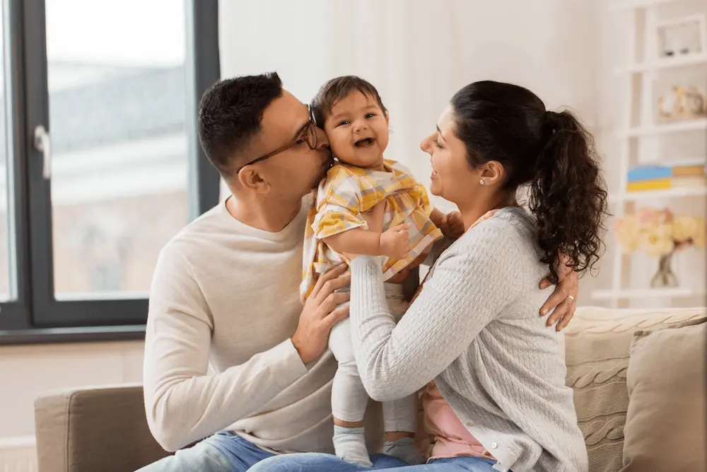 Two adults holding a smiling baby